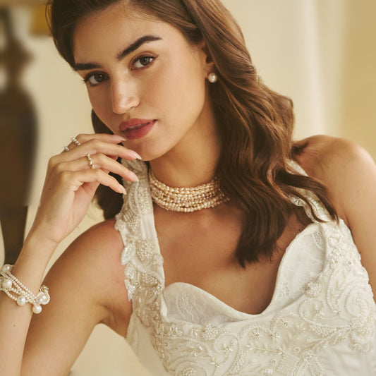 Model in an ivory embroidered corset gown wearing the Rosé Cascade pink freshwater pearl choker with pearl studs and bracelet - CherishBox